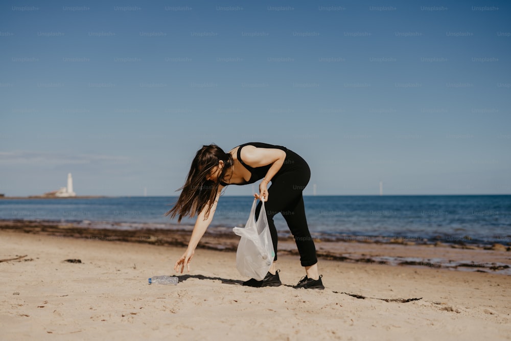 a woman bending over with a bag on a beach