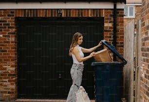 a woman standing next to a blue trash can