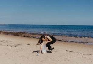 a woman kneeling down on a beach next to the ocean