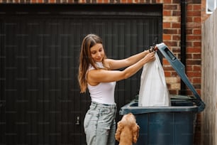 a woman putting a bag into a trash can