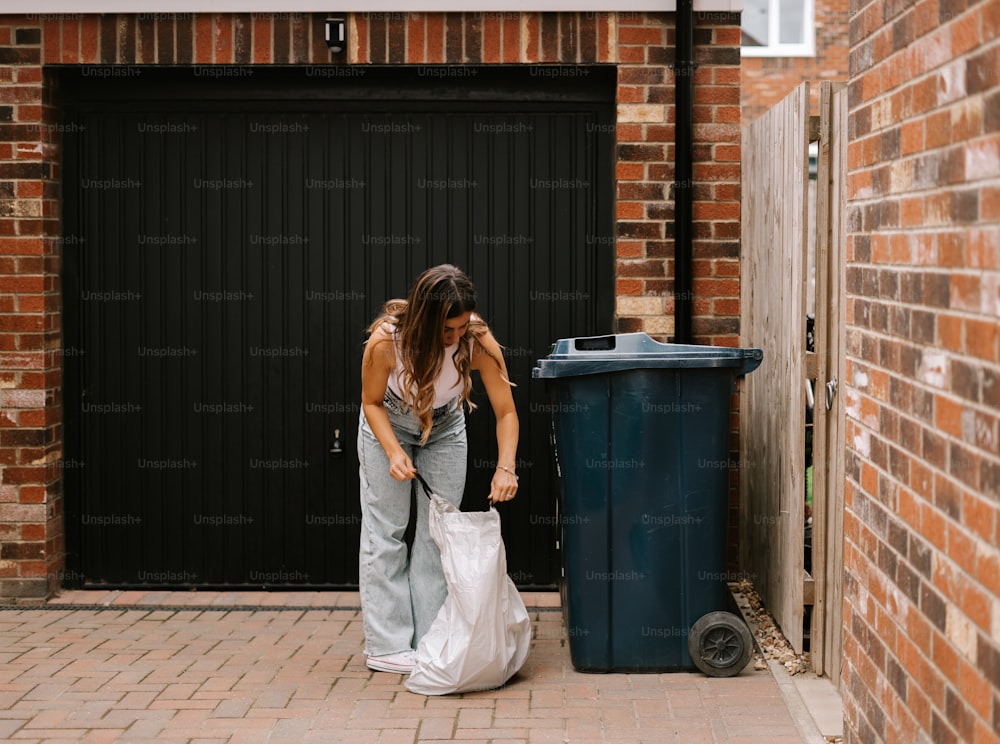 uma mulher ao lado de uma lata de lixo