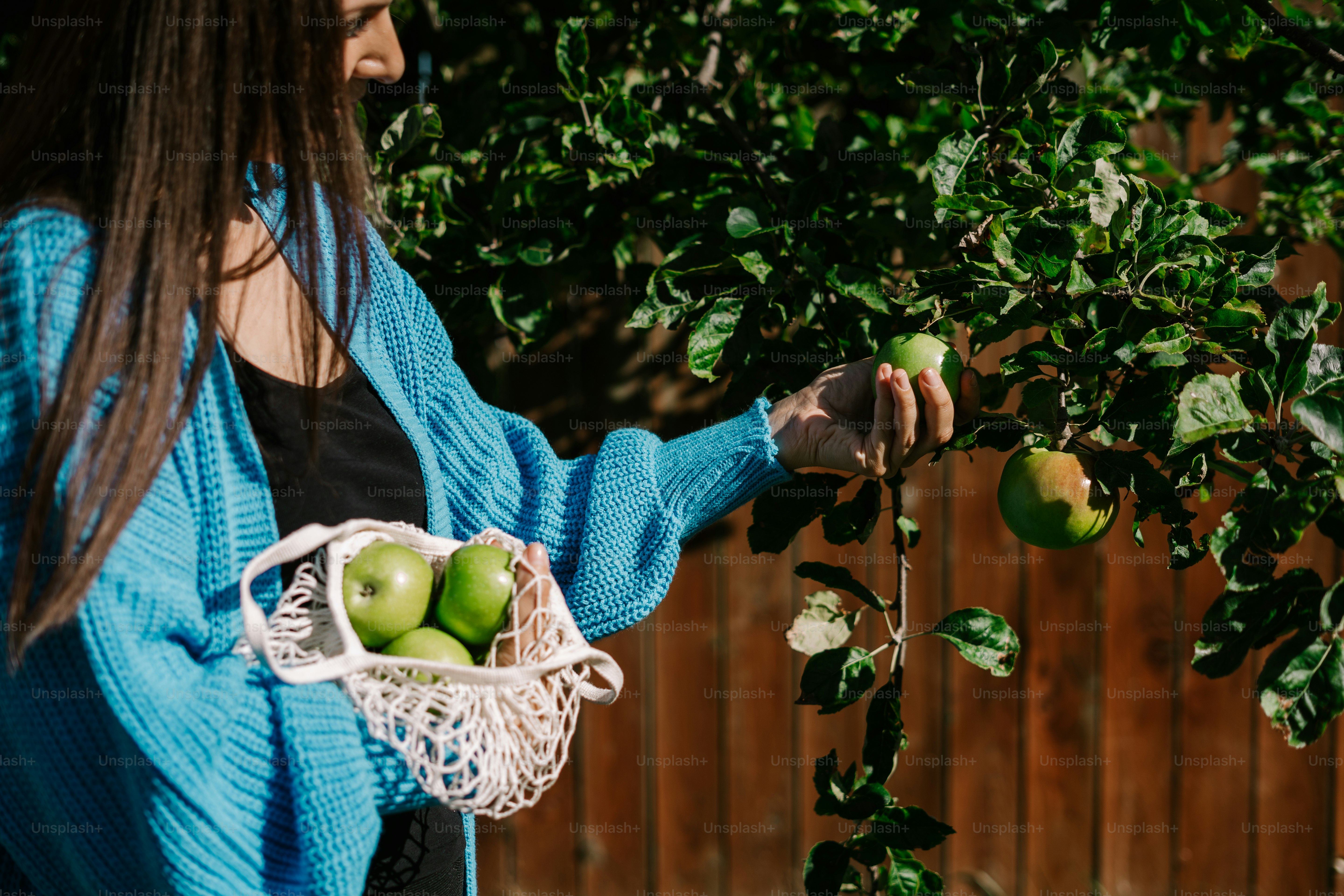 a woman holding a basket of green apples