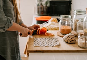 a woman is cutting an orange on a cutting board