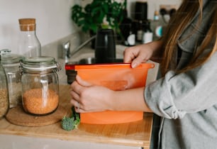 a woman is holding an orange container in her hands