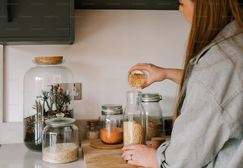 a woman standing in front of a counter filled with jars