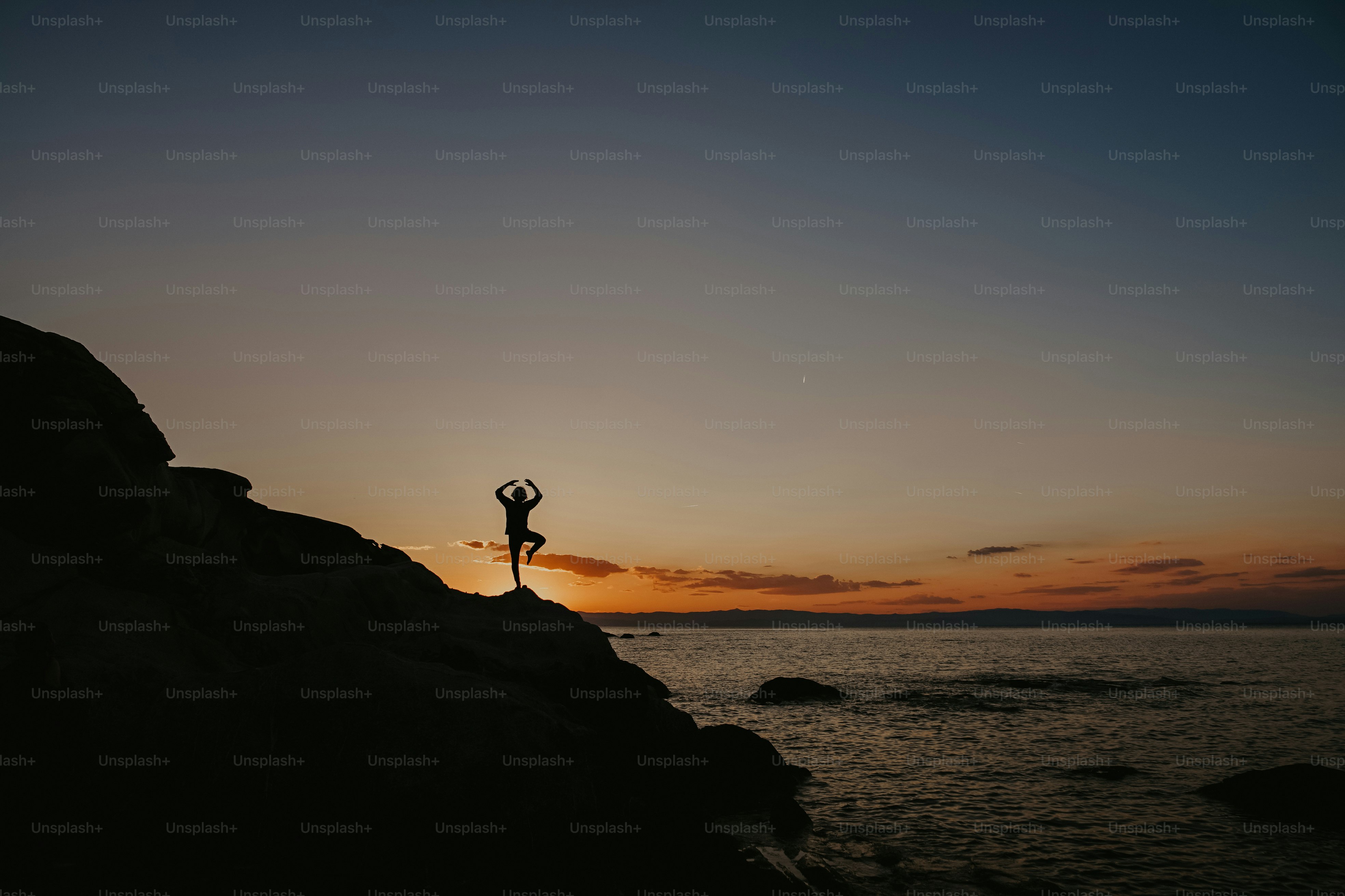 a person standing on top of a rock next to the ocean