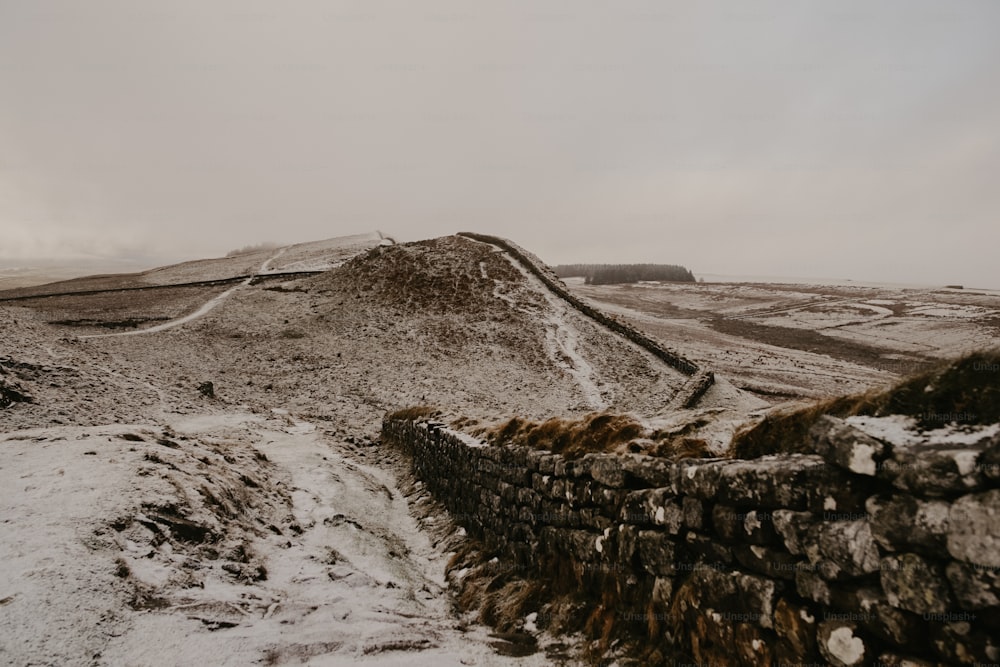 Una montaña cubierta de nieve con un muro de piedra