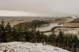 a snow covered hill with a lake in the distance