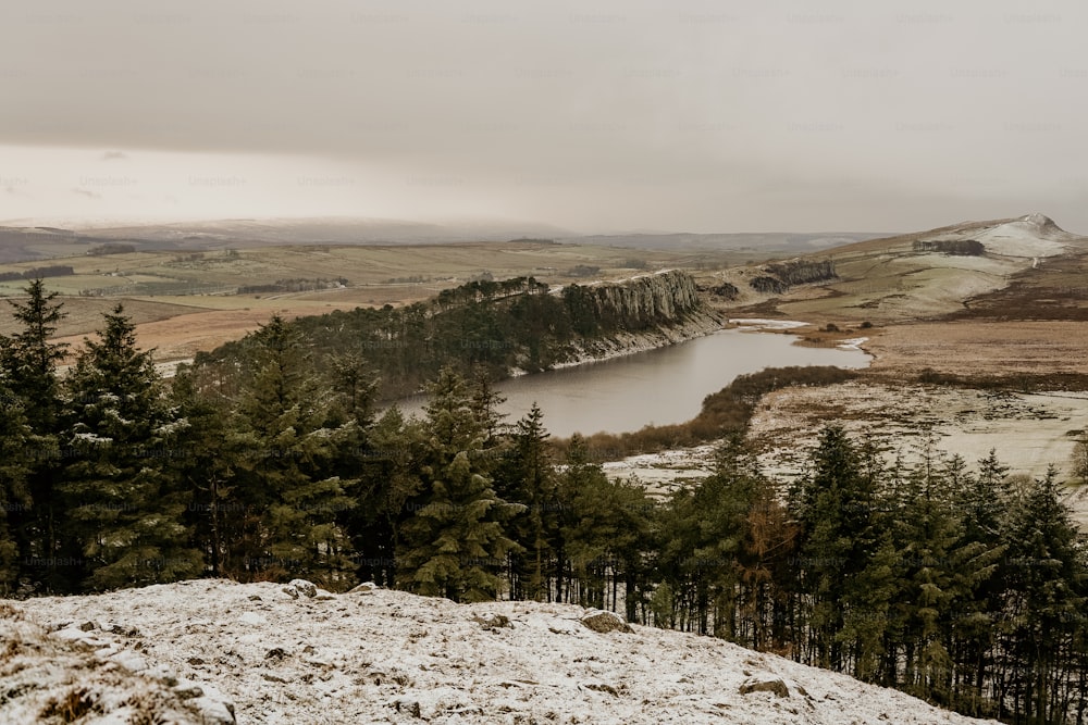 a snow covered hill with a lake in the distance