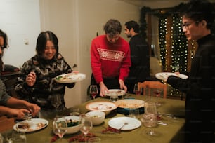 a group of people standing around a table with plates of food