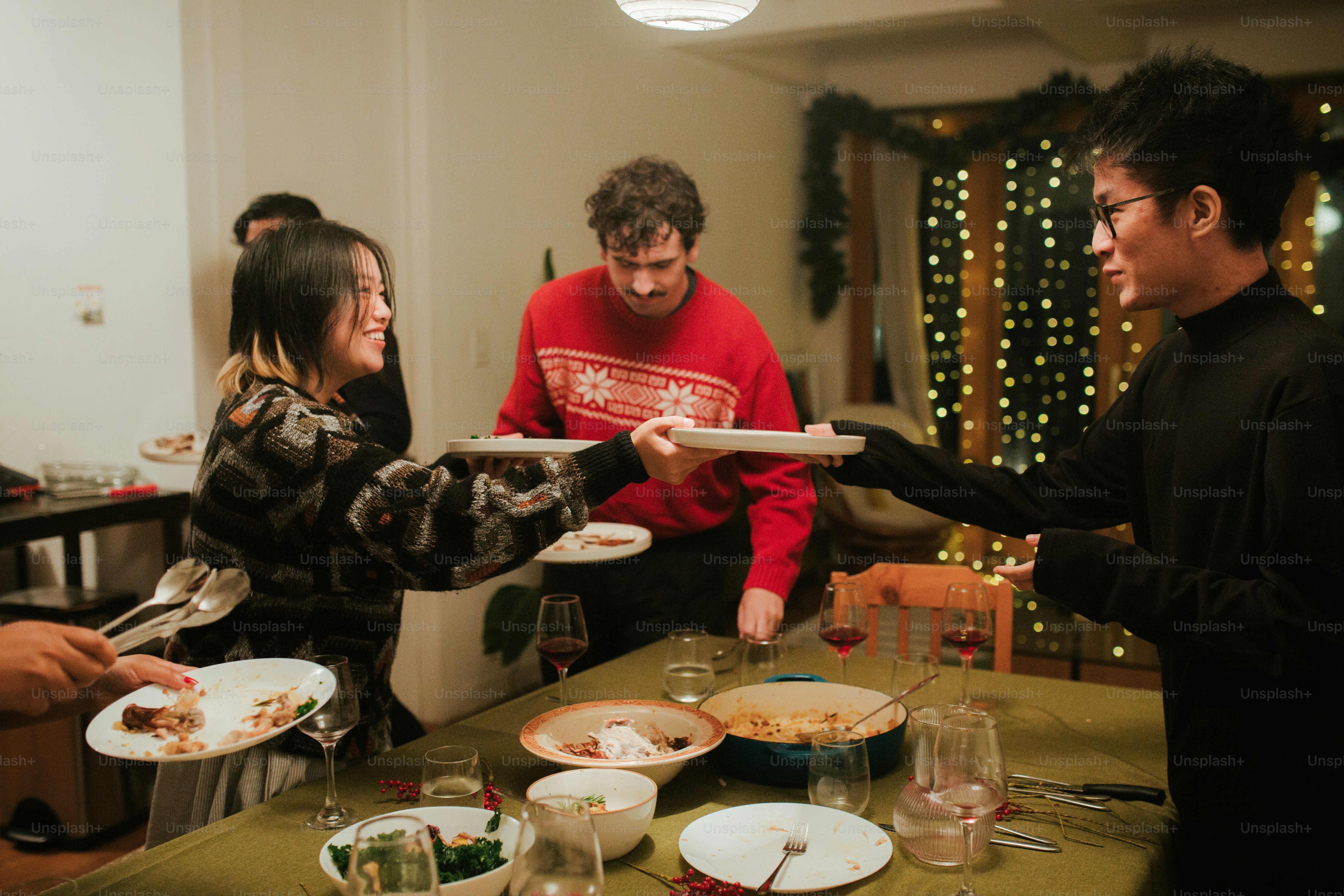 A group of people standing around a table with plates of food photo ...