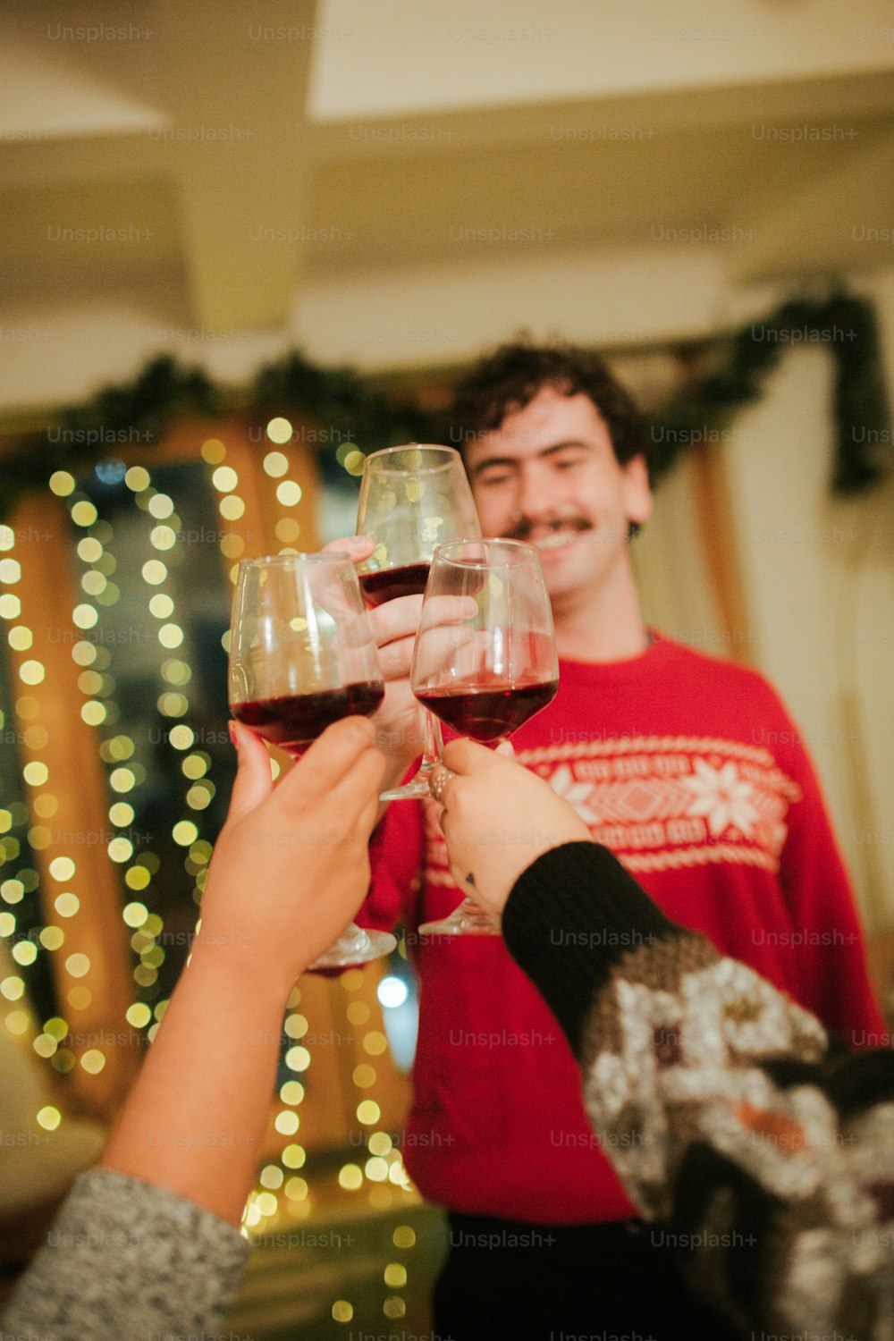 Deux personnes trinquent avec du vin rouge devant un sapin de Noël