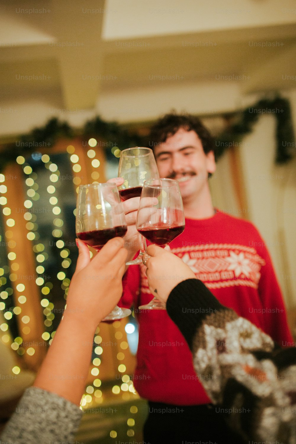 two people toasting with red wine in front of a christmas tree