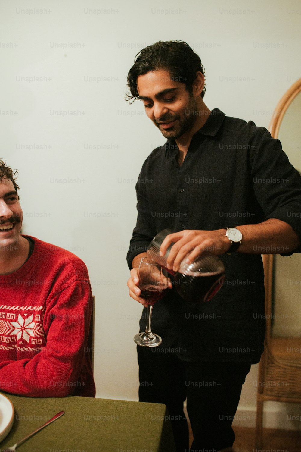 a man pouring a glass of wine to another man