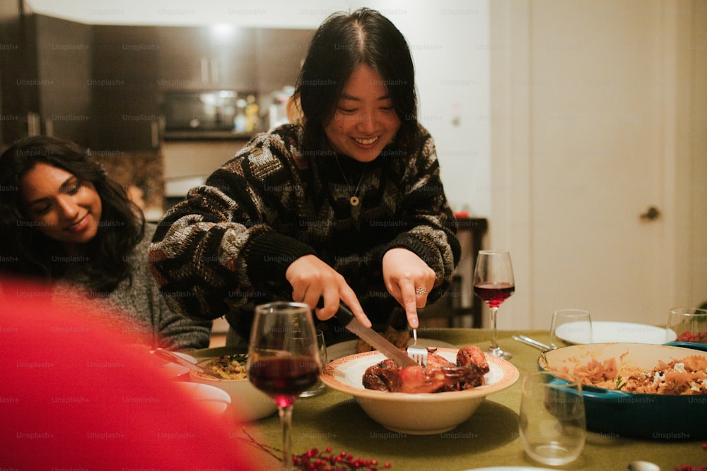 a woman cutting a piece of meat with a knife and fork