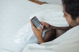 a man laying in bed with a cell phone in his hand
