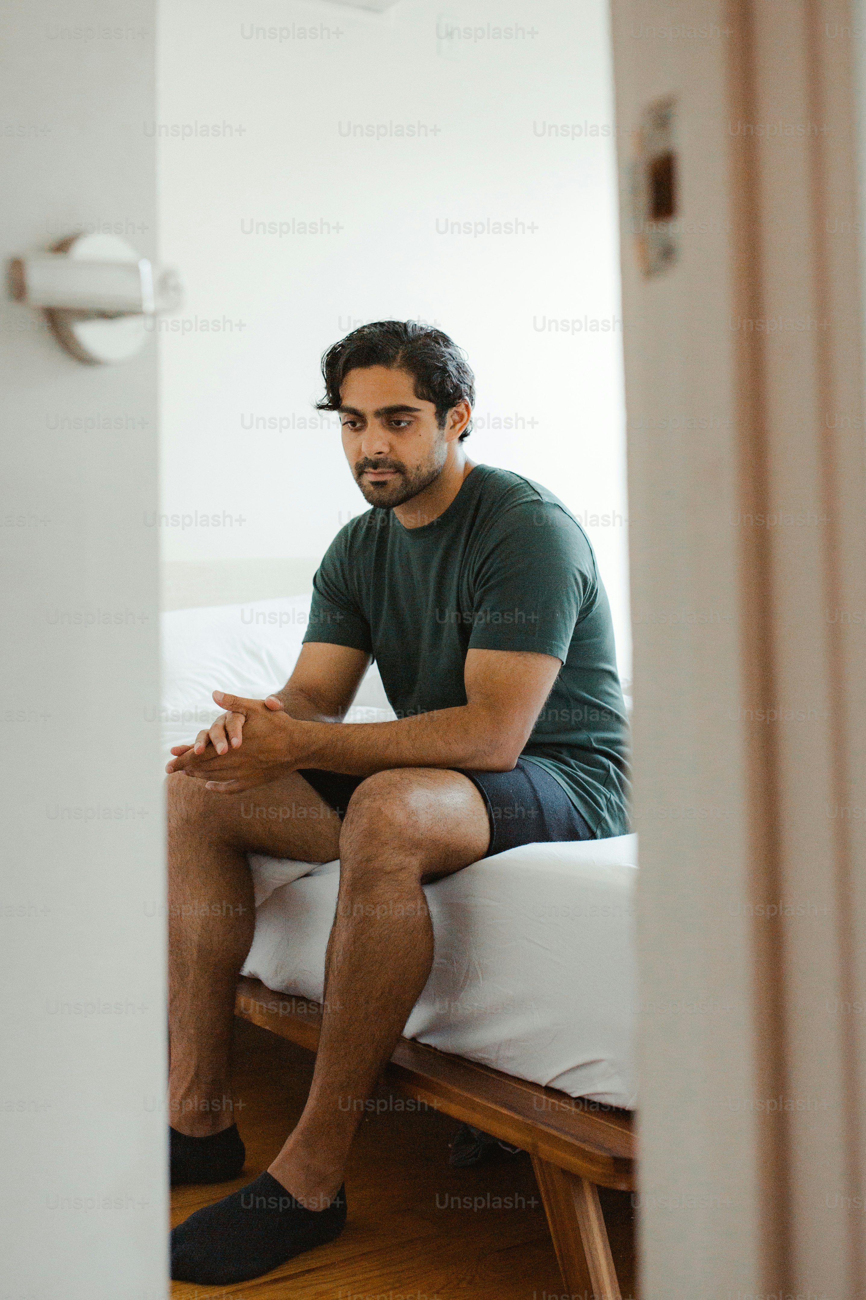 Un hombre sentado encima de una cama en una habitación