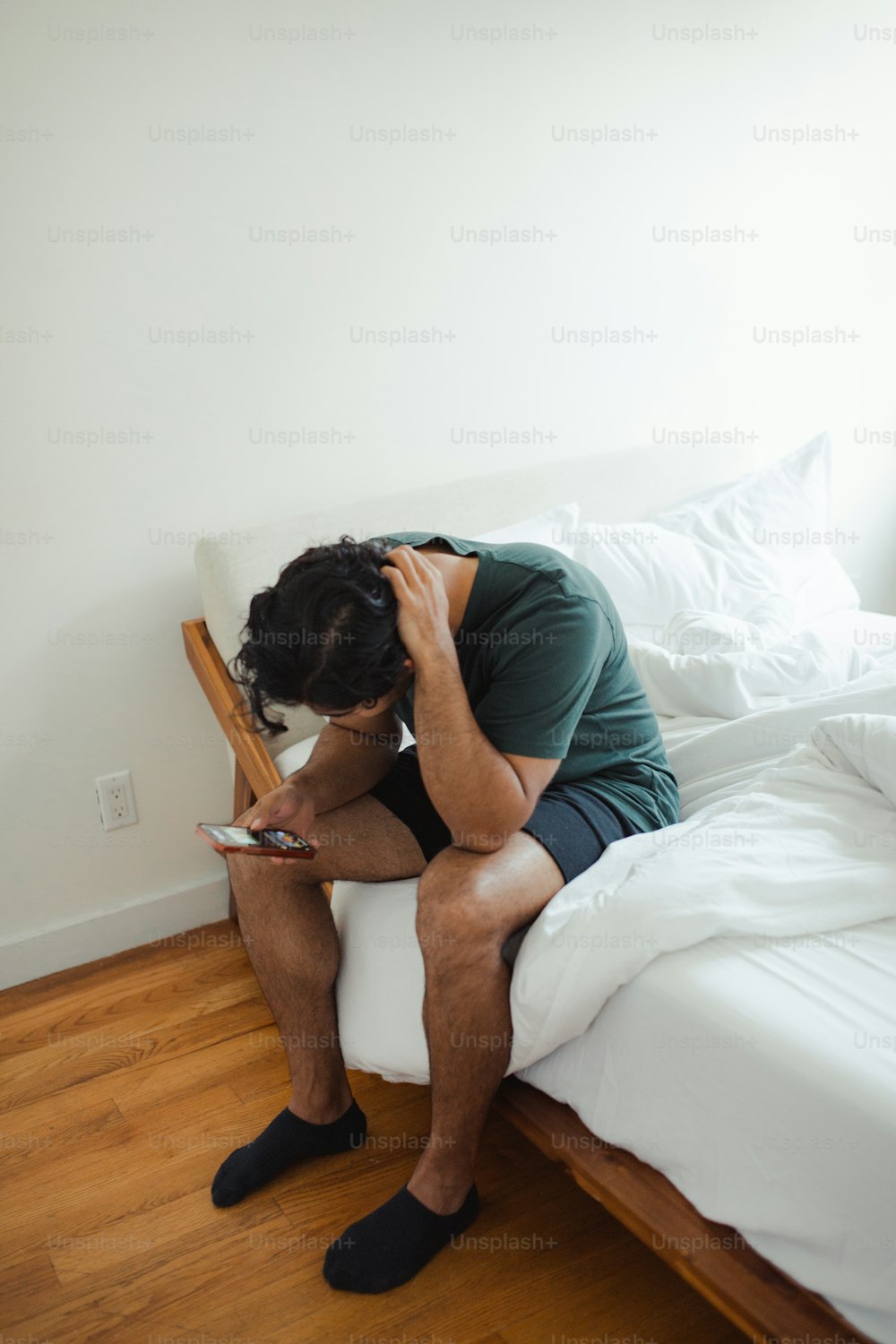 a man sitting on a bed looking at his cell phone