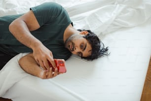 a man laying on a bed holding a cell phone