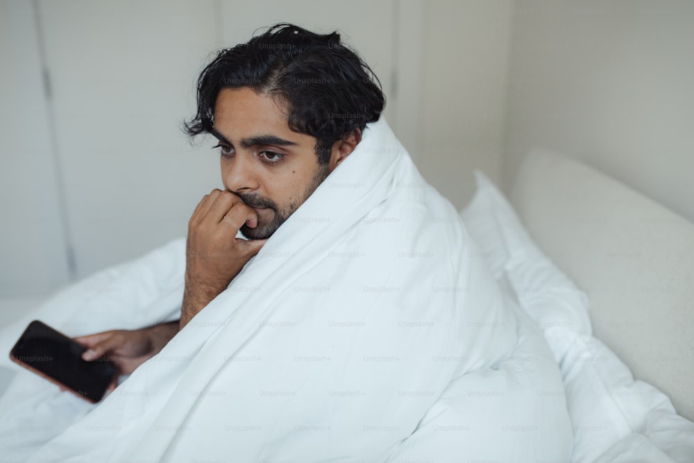 a man laying in bed with a remote control in his hand