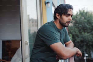 a man with a guitar leaning against a window