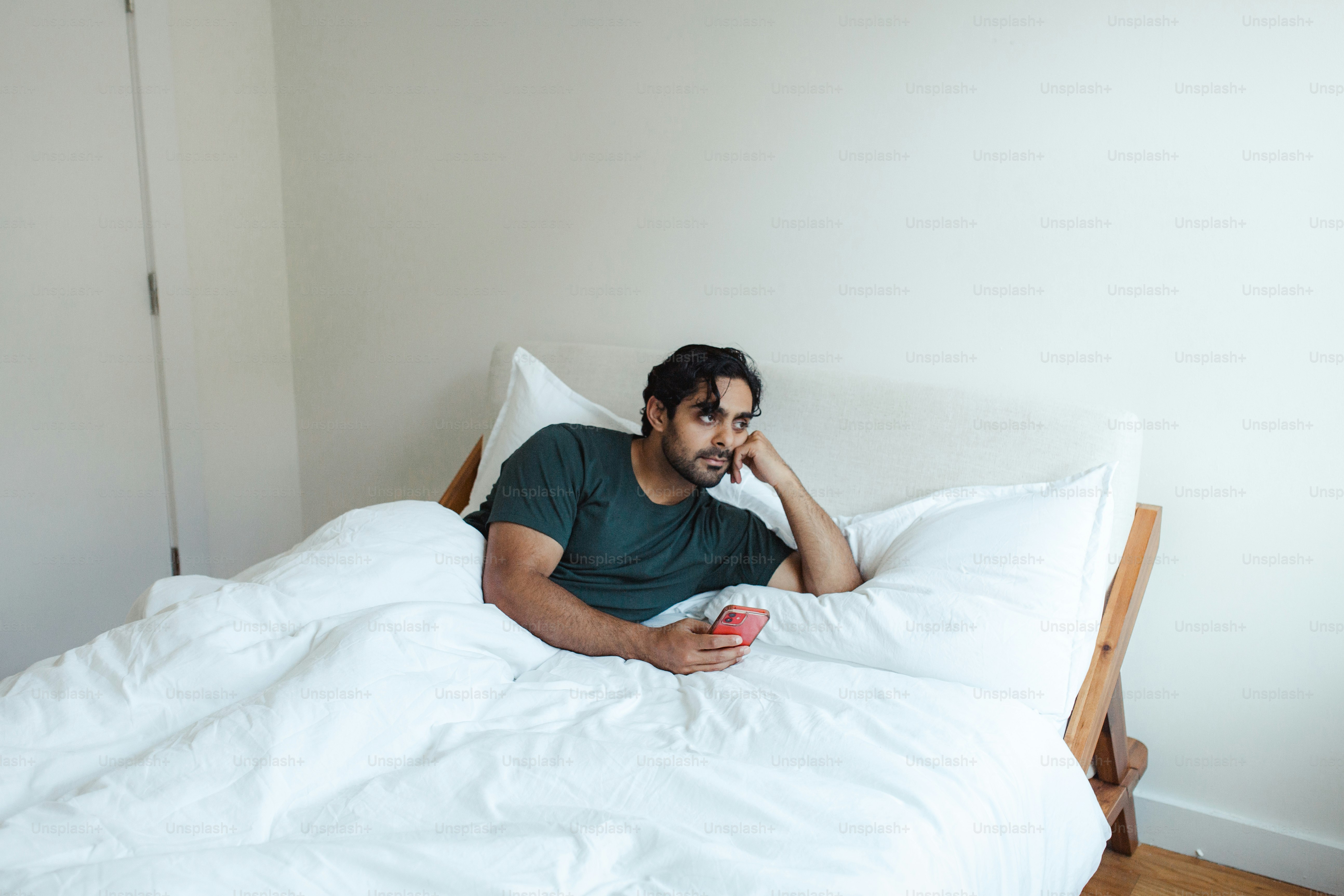 a man laying in bed with a cup of coffee