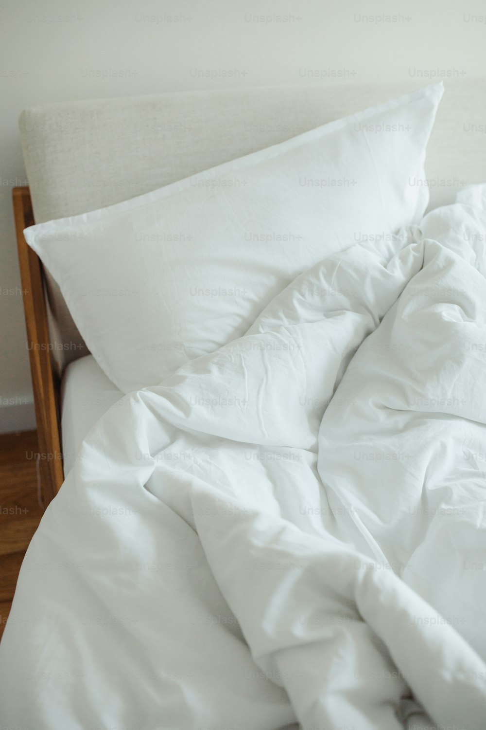 an unmade bed with white sheets and pillows