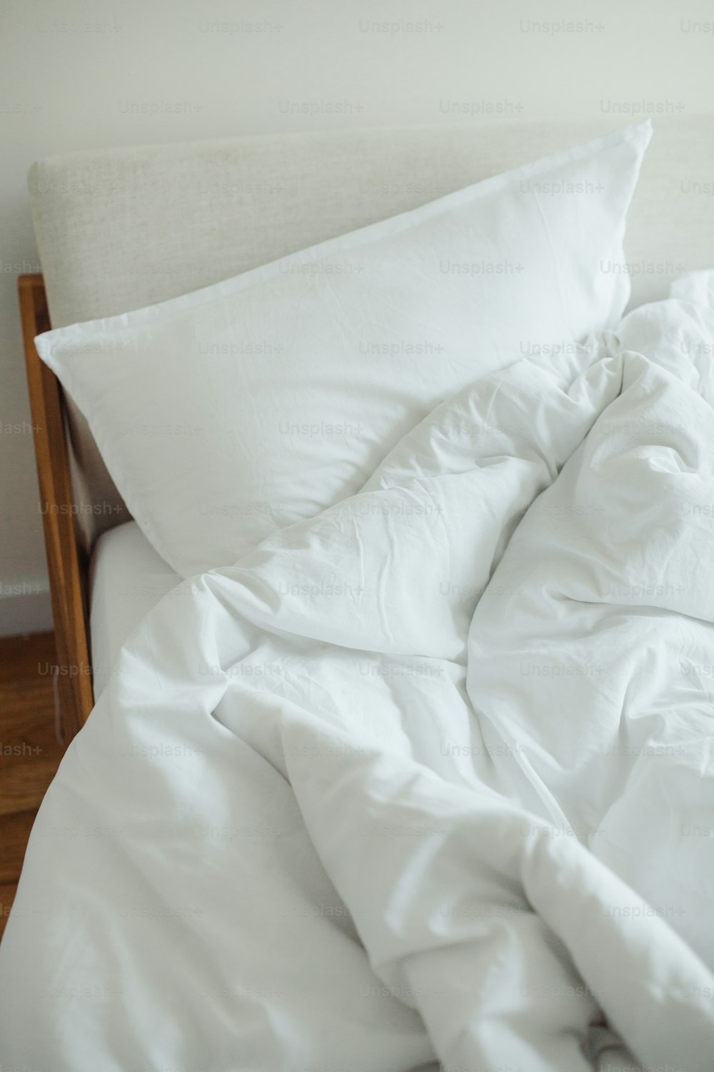 ein ungemachtes Bett mit weißen Laken und Kissen