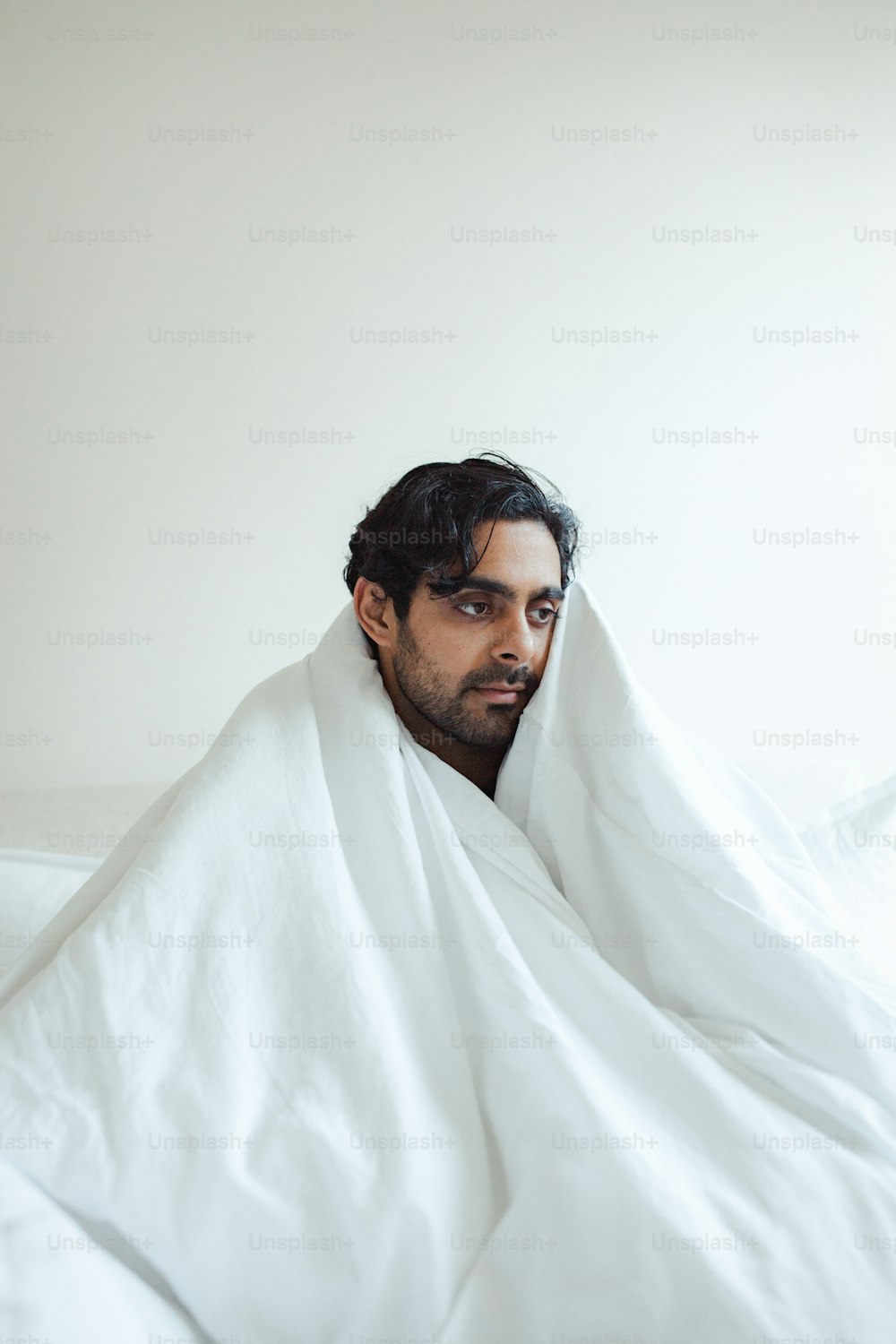 um homem enrolado em um cobertor em cima de uma cama