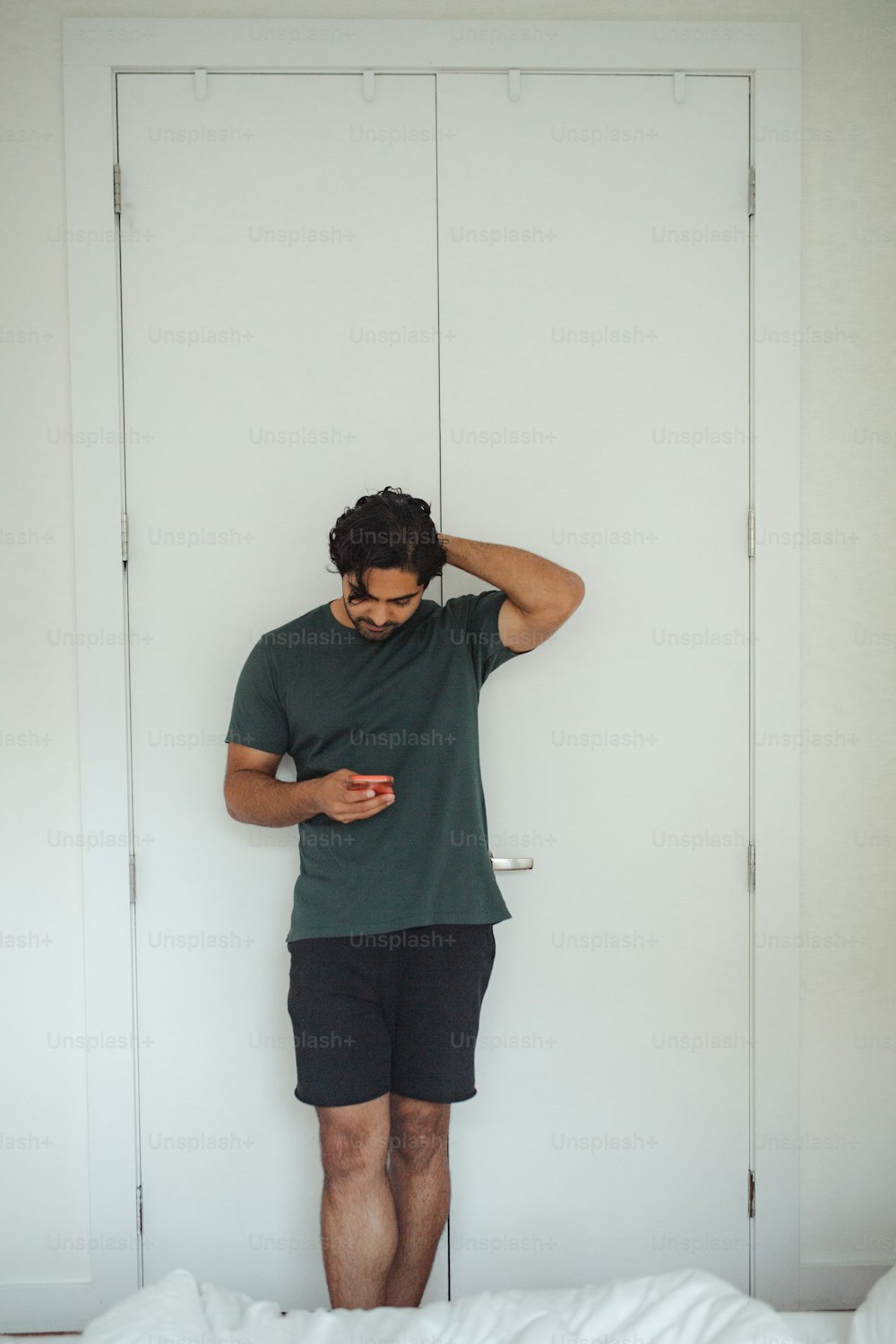 um homem parado em frente a uma porta olhando para seu celular
