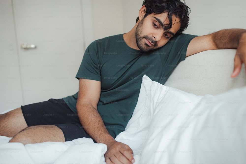 a man sitting on a bed with white sheets