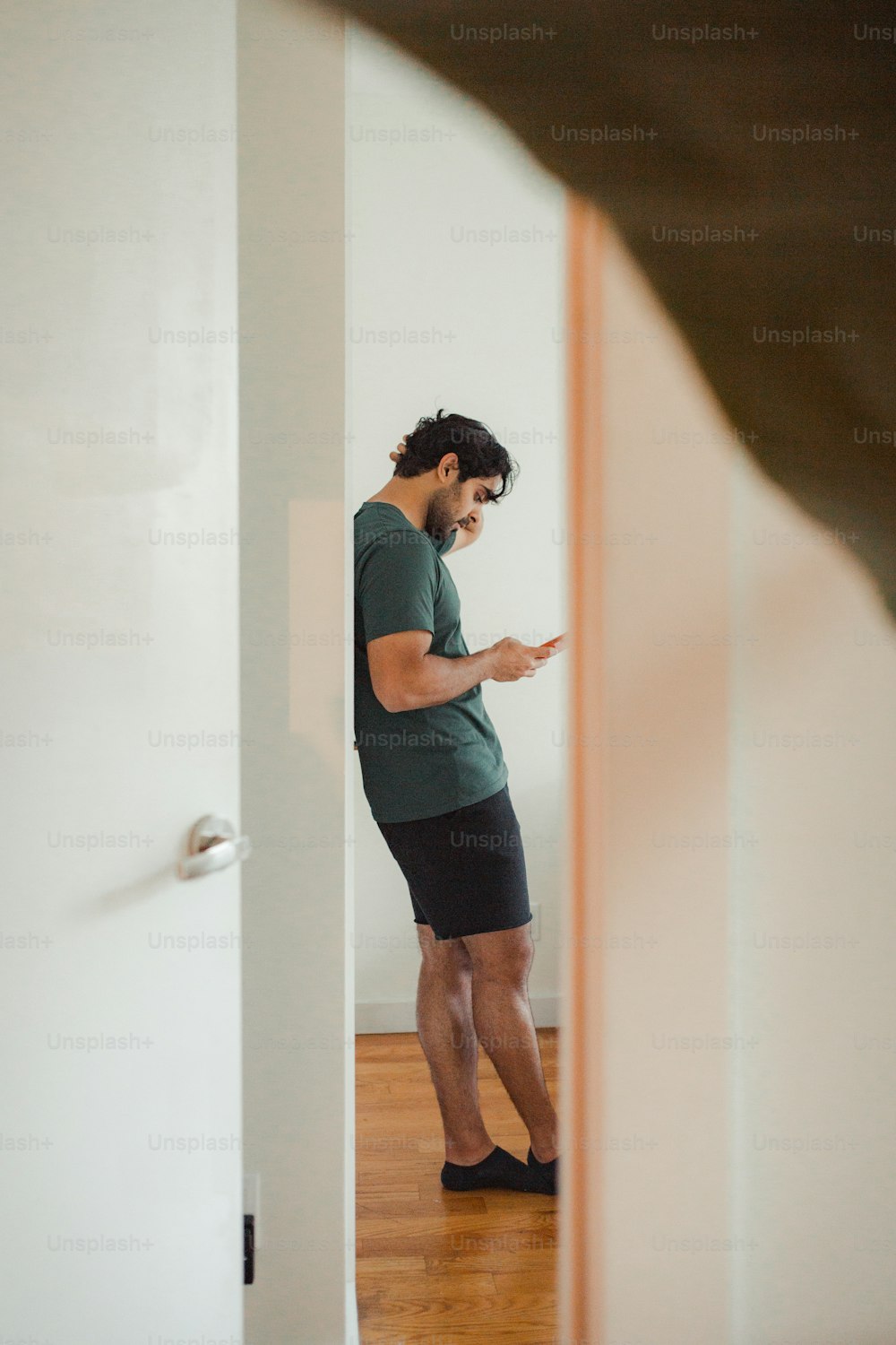 a man standing in a doorway looking at his cell phone