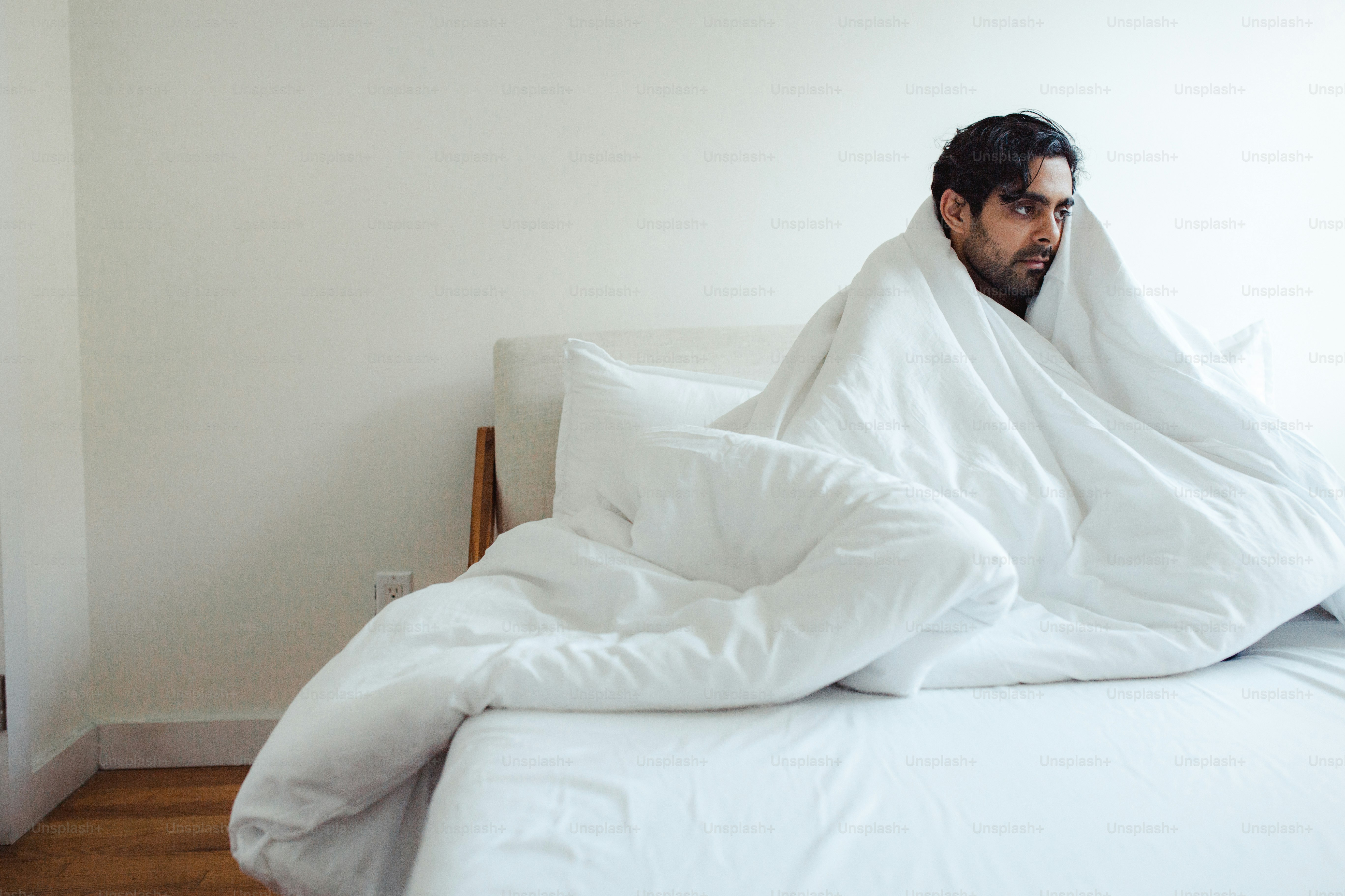 A man wrapped in a blanket on top of a bed photo Mental health