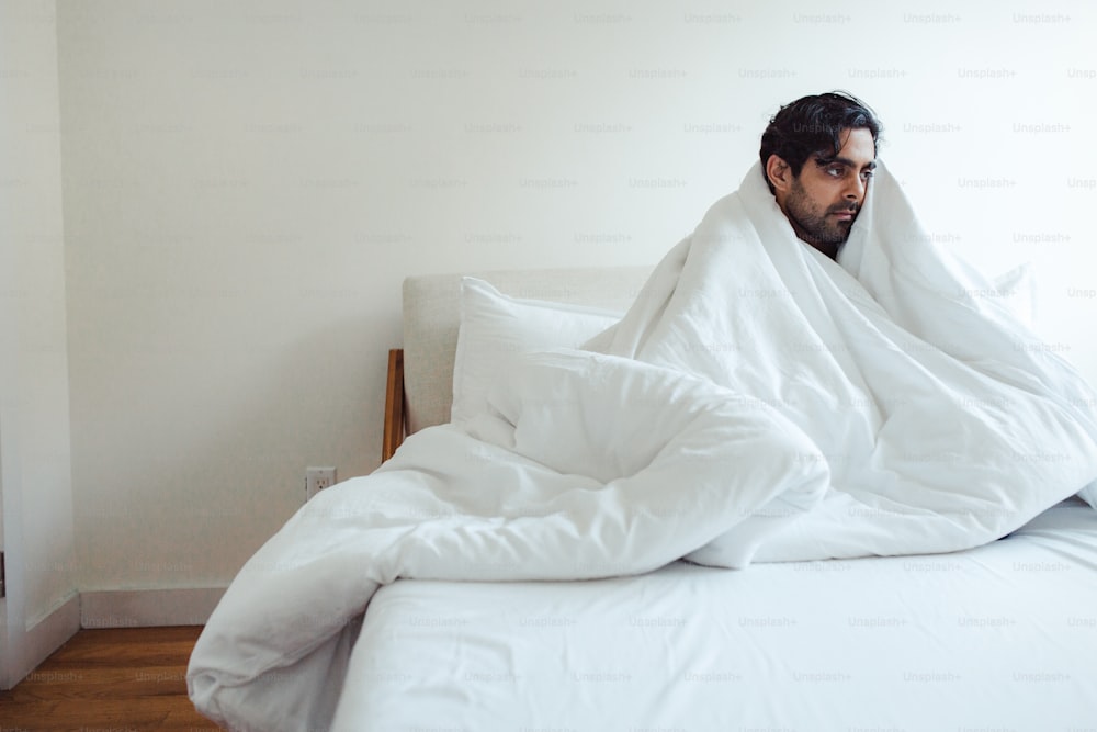 a man wrapped in a blanket on top of a bed