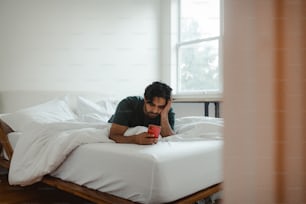 a man laying on a bed looking at his cell phone