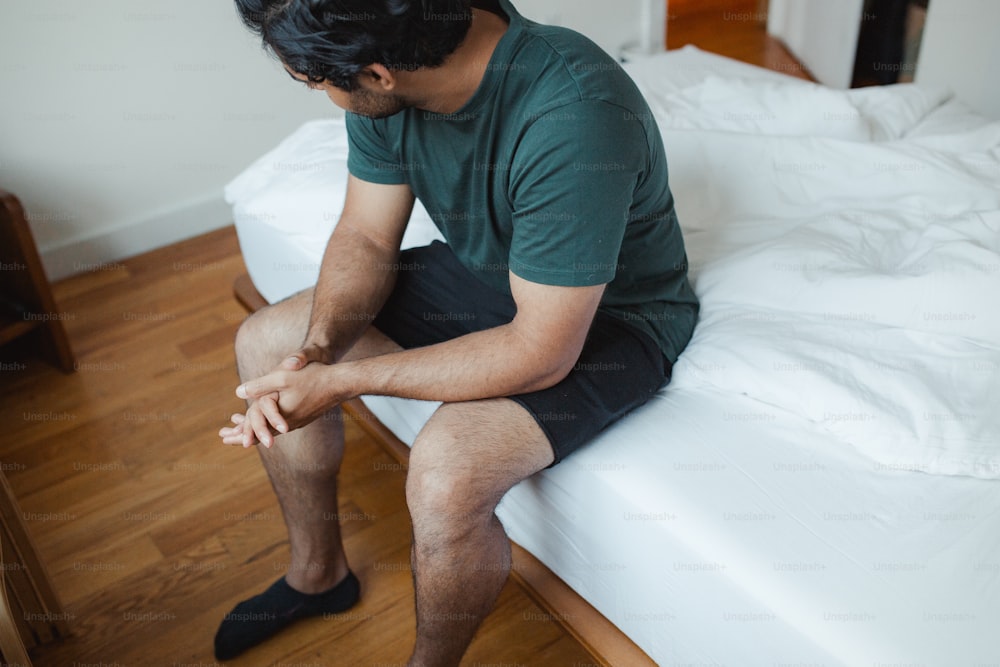 um homem sentado em uma cama com as pernas cruzadas
