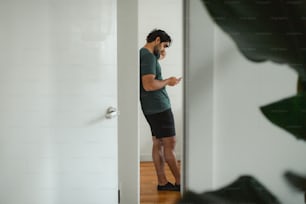 a man standing in a doorway looking at his cell phone