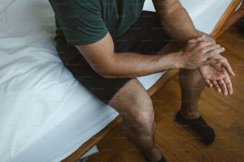 Un homme assis sur un lit, les mains sur les genoux
