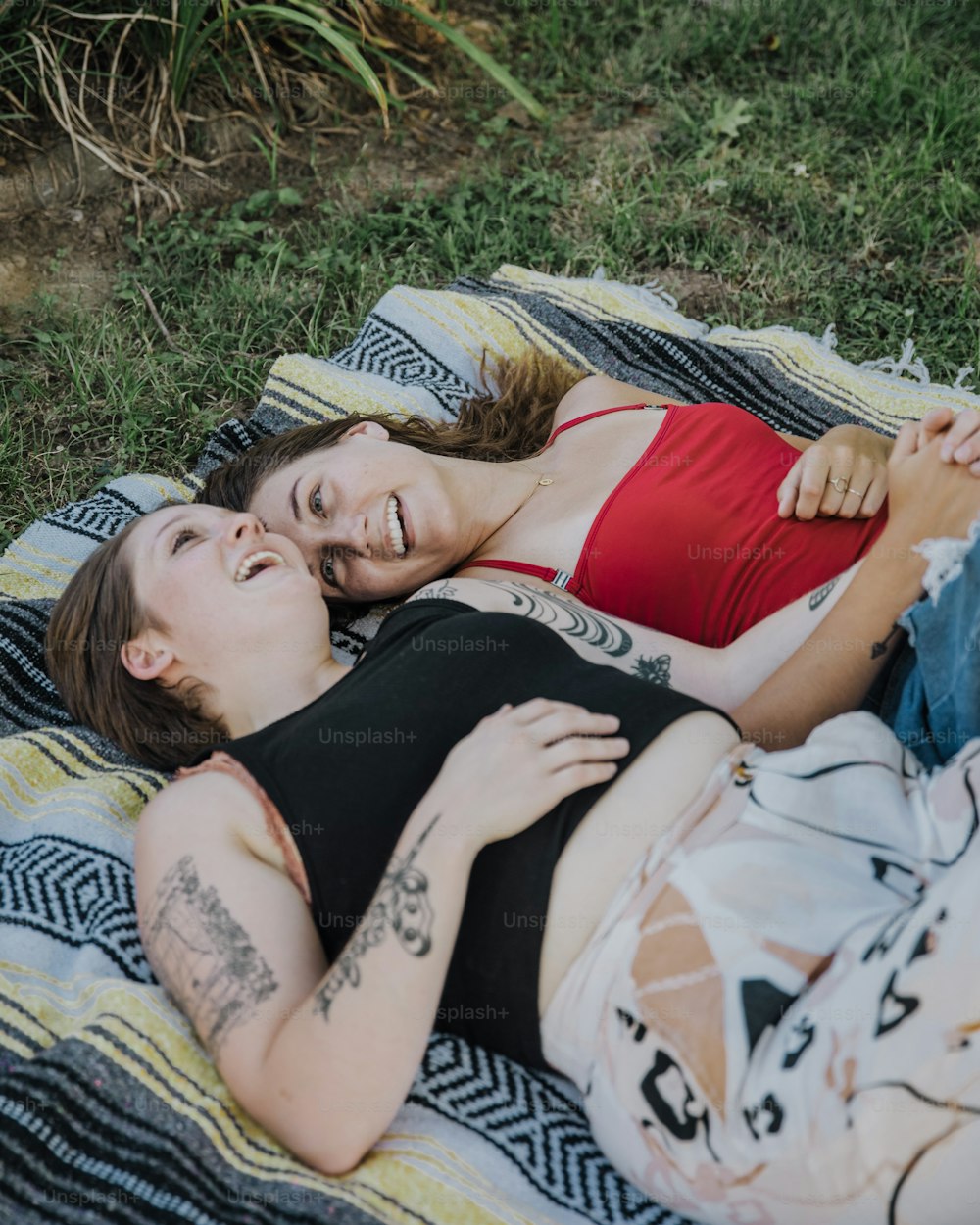 a couple of women laying on top of a blanket