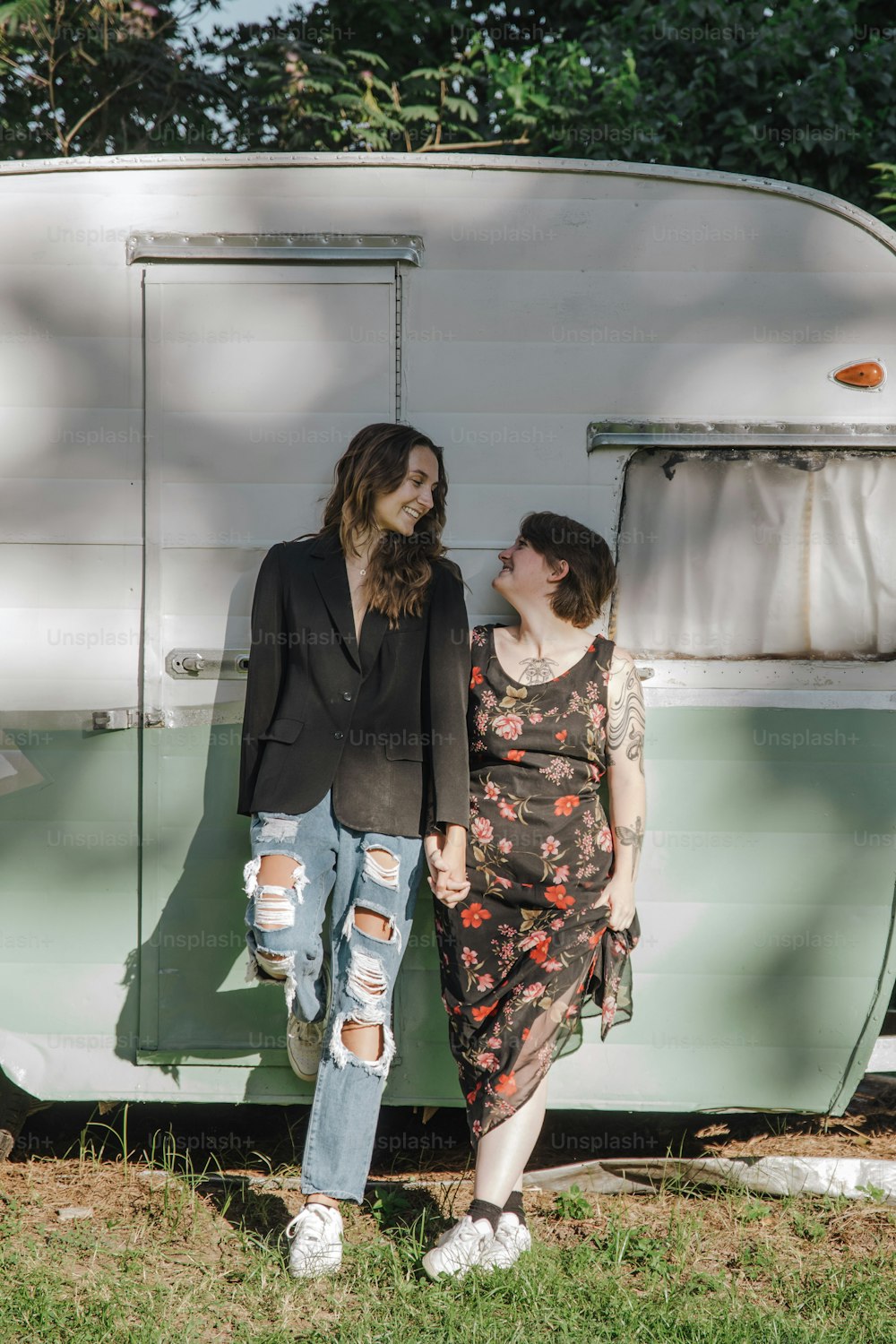 um casal de mulheres em pé um ao lado do outro em frente a um trailer
