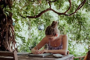 a woman sitting at a table writing on a piece of paper