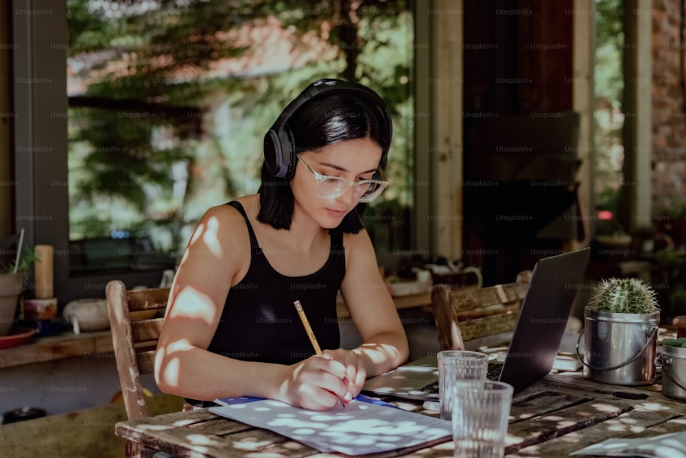 Eine Frau, die an einem Tisch sitzt und an einem Laptop arbeitet