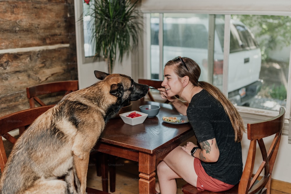 une femme assise à une table avec un chien