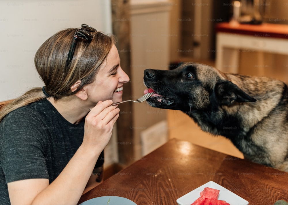 Una mujer alimentando a un perro sandía con una cuchara