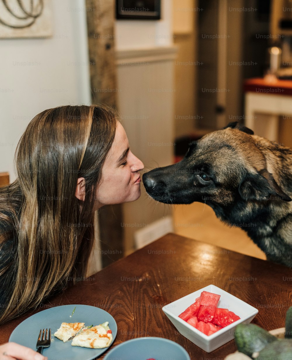 a woman kissing a dog on the nose