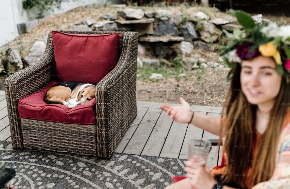 a woman sitting on a patio with a dog in a chair