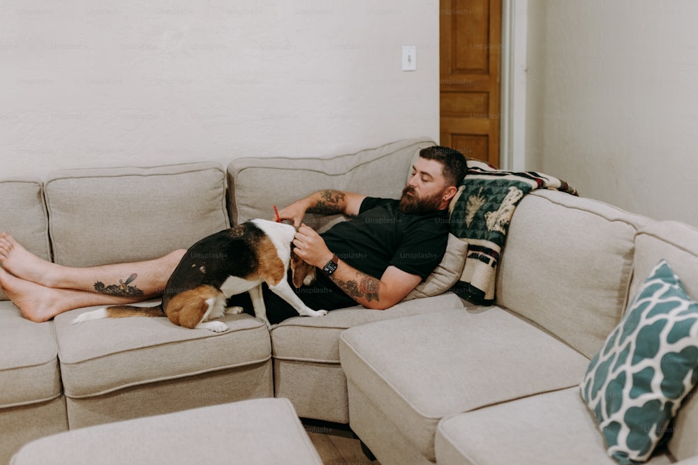 a man laying on top of a couch next to a dog