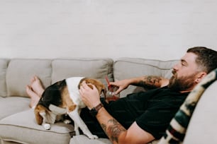 Un hombre sentado en un sofá acariciando a un perro