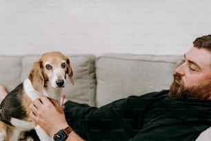 a man laying on a couch petting a dog