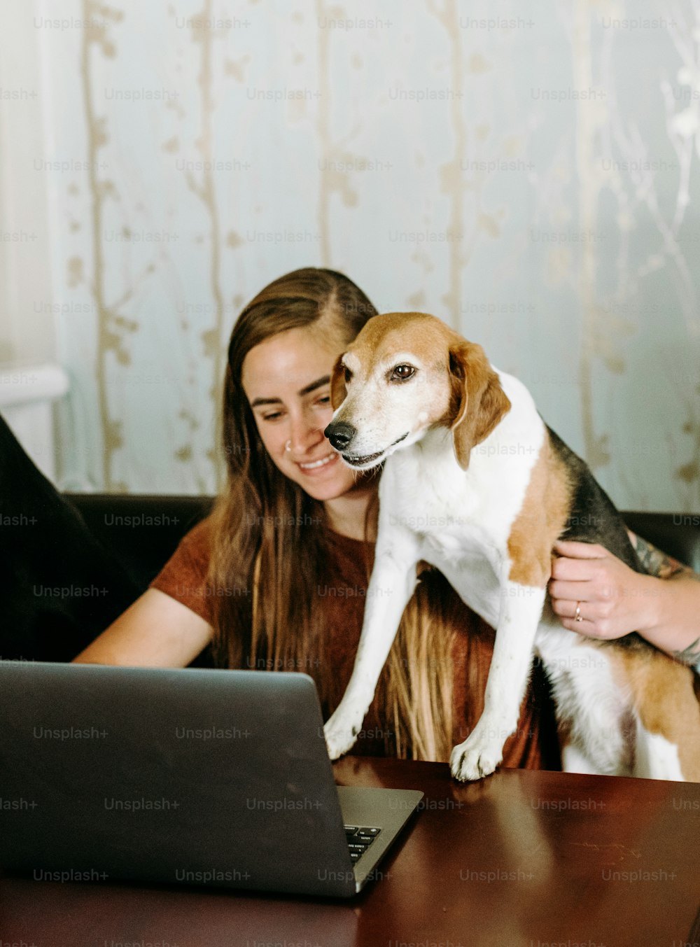 Une femme assise à une table avec un chien sur ses genoux